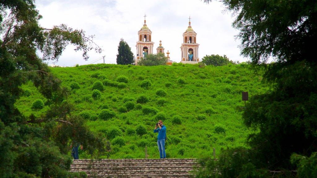 Gran Pirámide de Cholula ofreciendo una iglesia o catedral y escenas tranquilas y también un hombre