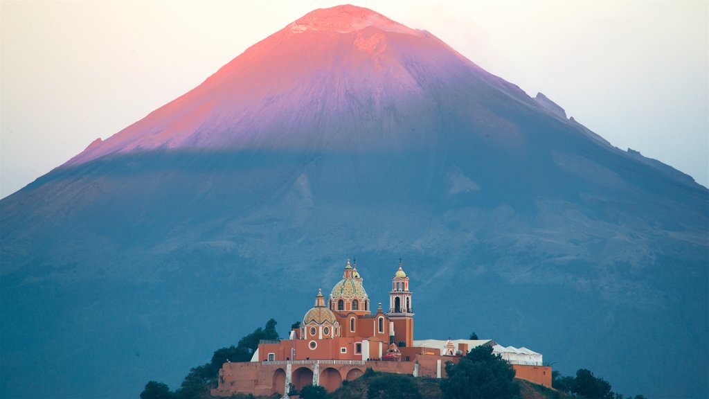 Santuario de La Virgen de los Remedios ofreciendo una puesta de sol, montañas y elementos del patrimonio