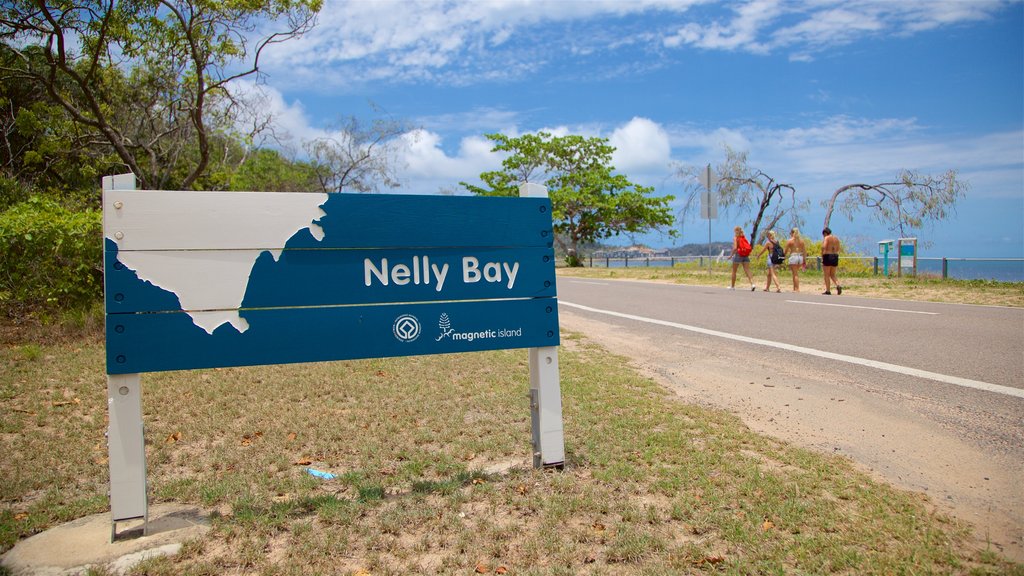 Nelly Bay mostrando paisagens litorâneas e sinalização assim como um pequeno grupo de pessoas