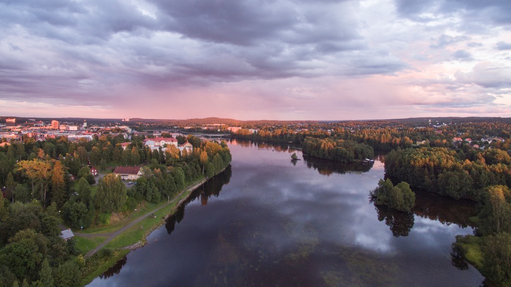 Skelleftea inclusief een zonsondergang, een rivier of beek en een stad