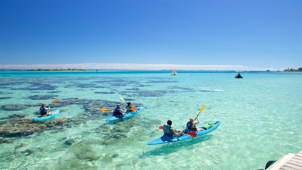 Playa Tiahura ofreciendo vistas generales de la costa y kayak o canoa y también un pequeño grupo de personas