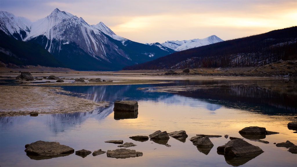 Lago Medicine que incluye una puesta de sol, nieve y montañas