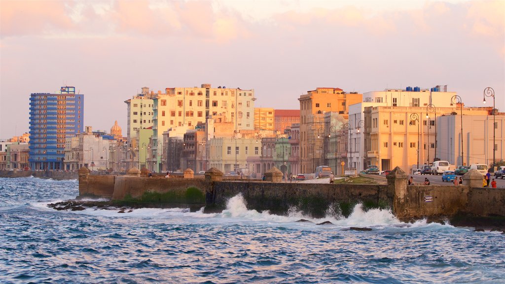 Malecón que incluye una ciudad, una bahía o un puerto y un atardecer