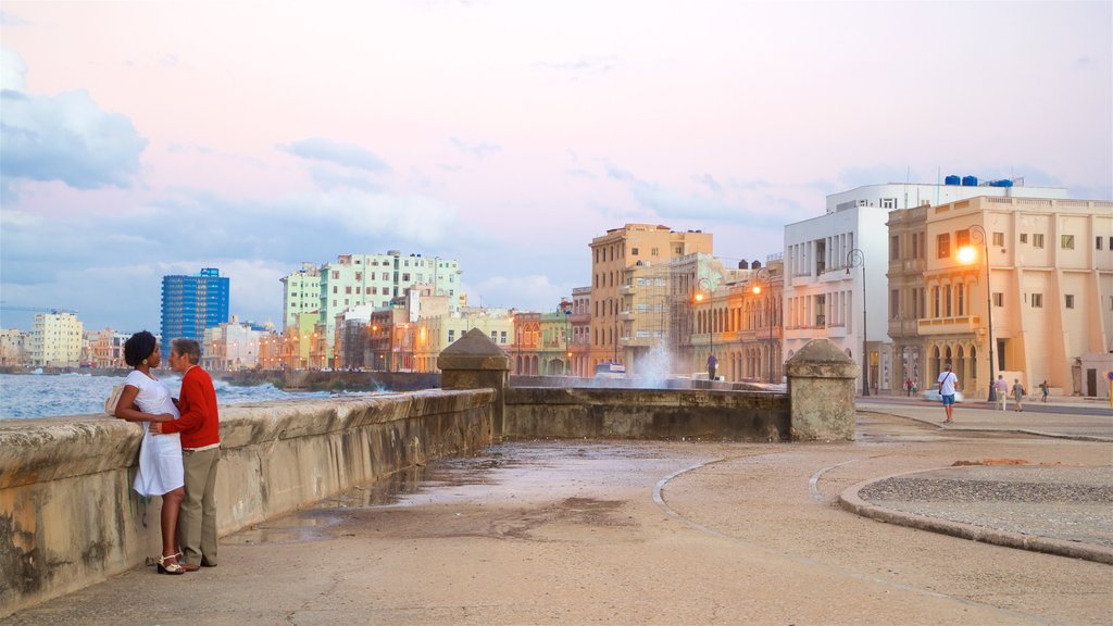 Malecón which includes a bay or harbour, a city and a sunset