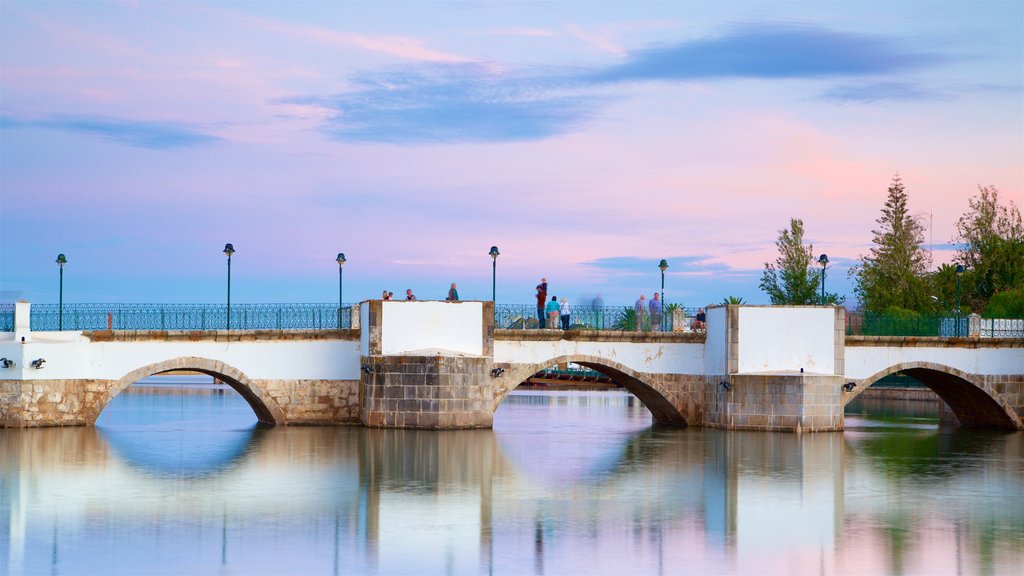 Puente romano ofreciendo una puesta de sol, un puente y un río o arroyo