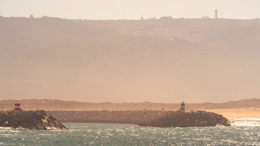 Playa de Nazaré que incluye un atardecer, vista general a la costa y niebla o neblina