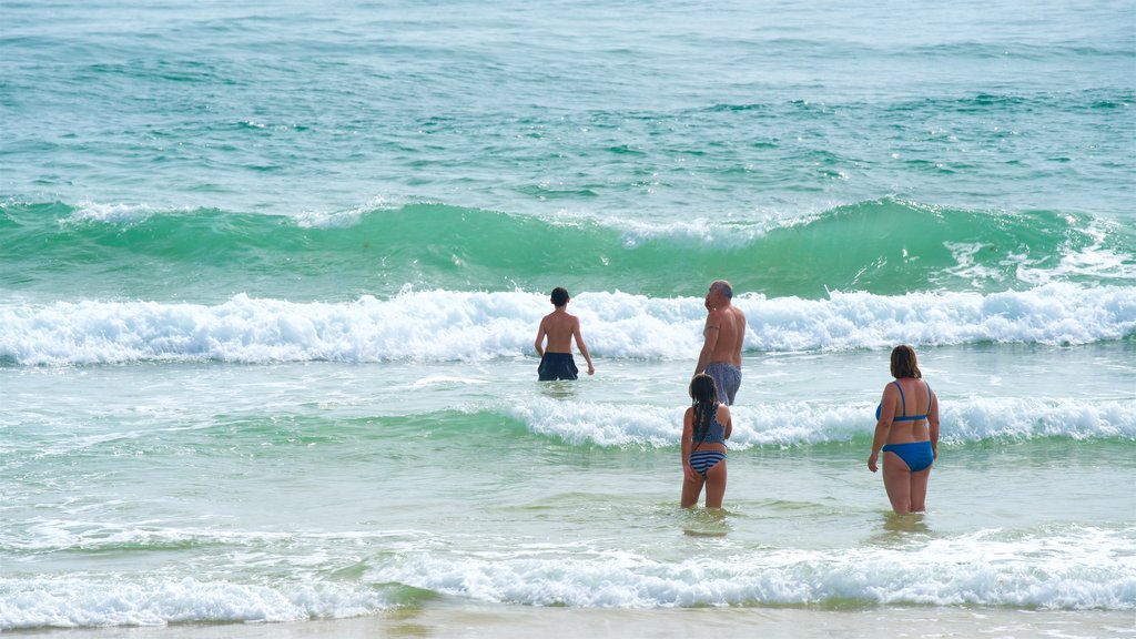 Playa Fuzeta ofreciendo olas y vista general a la costa y también una familia