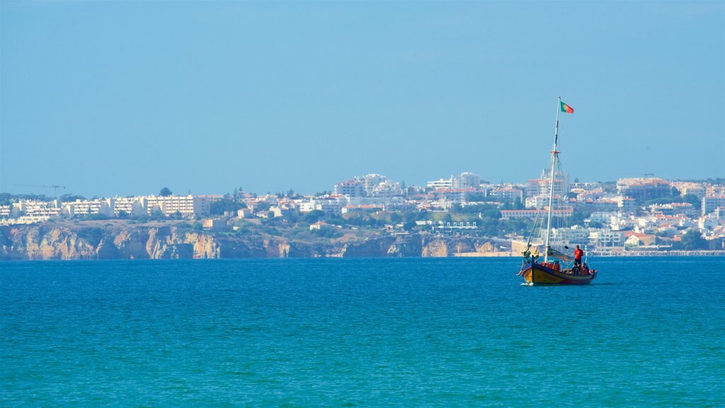 Playa de Alvor ofreciendo vista general a la costa, una ciudad costera y botes