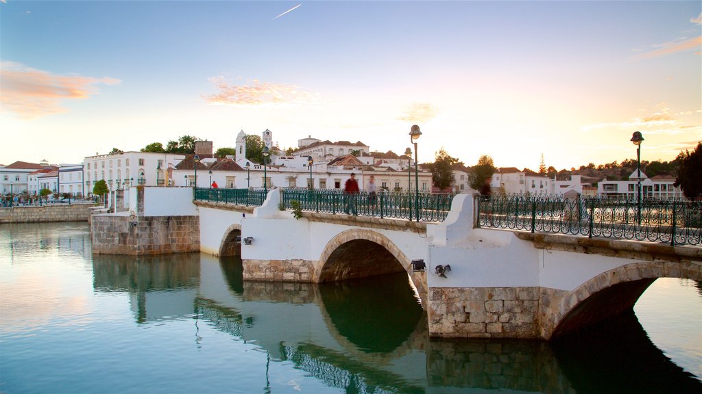 Puente romano que incluye un atardecer, un puente y un río o arroyo