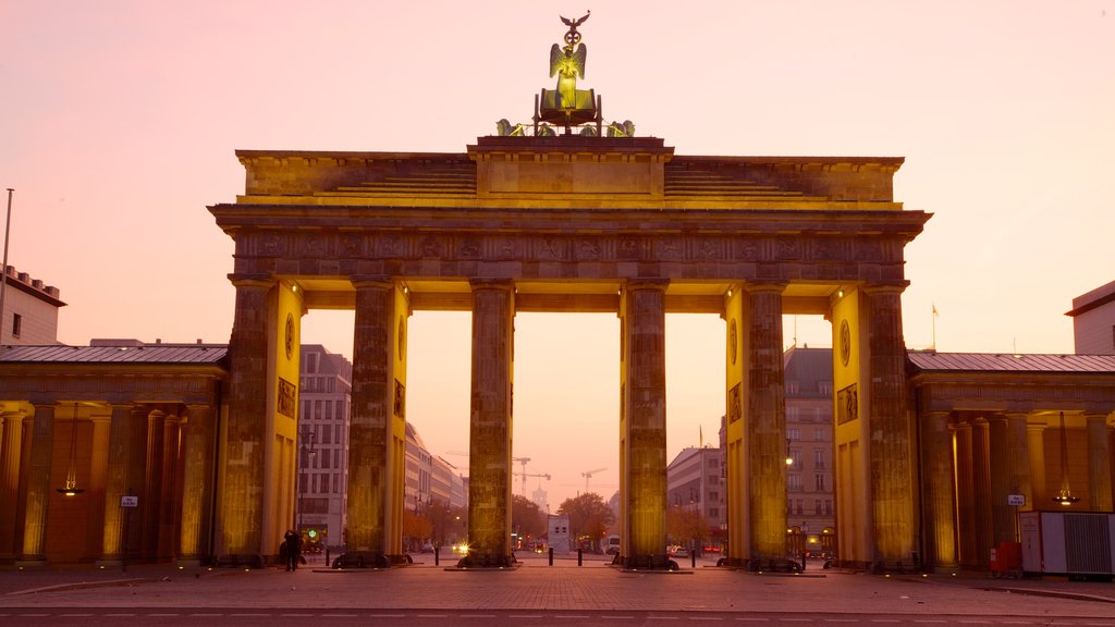 Portão de Brandenburgo que inclui um monumento, uma cidade e um pôr do sol