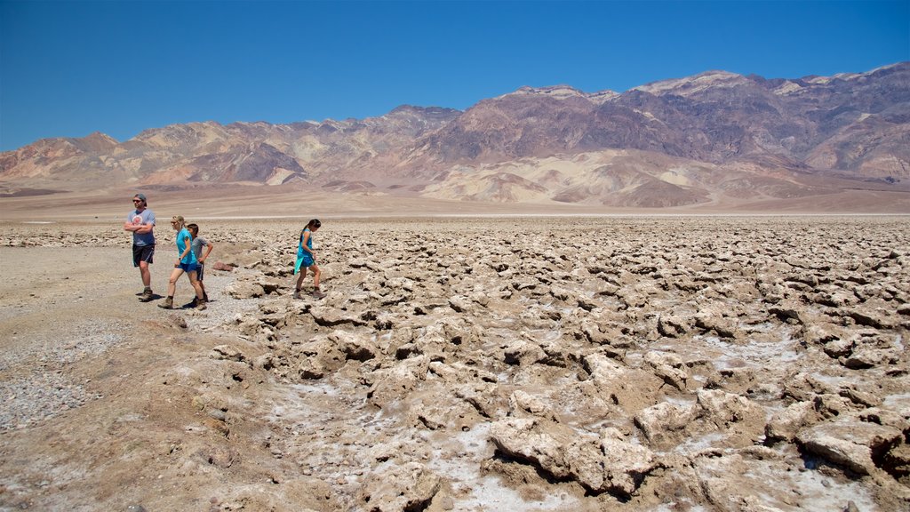 Devil\'s Golf Course mostrando vistas al desierto y vistas de paisajes y también un pequeño grupo de personas