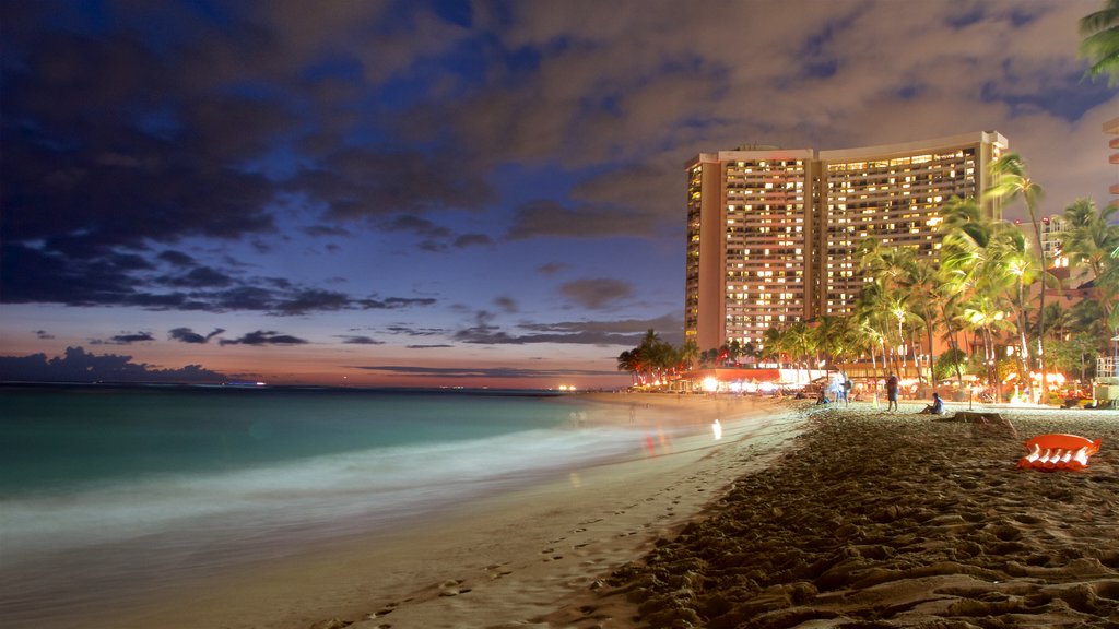 Waikiki Beach que incluye escenas nocturnas, una playa y una ciudad costera