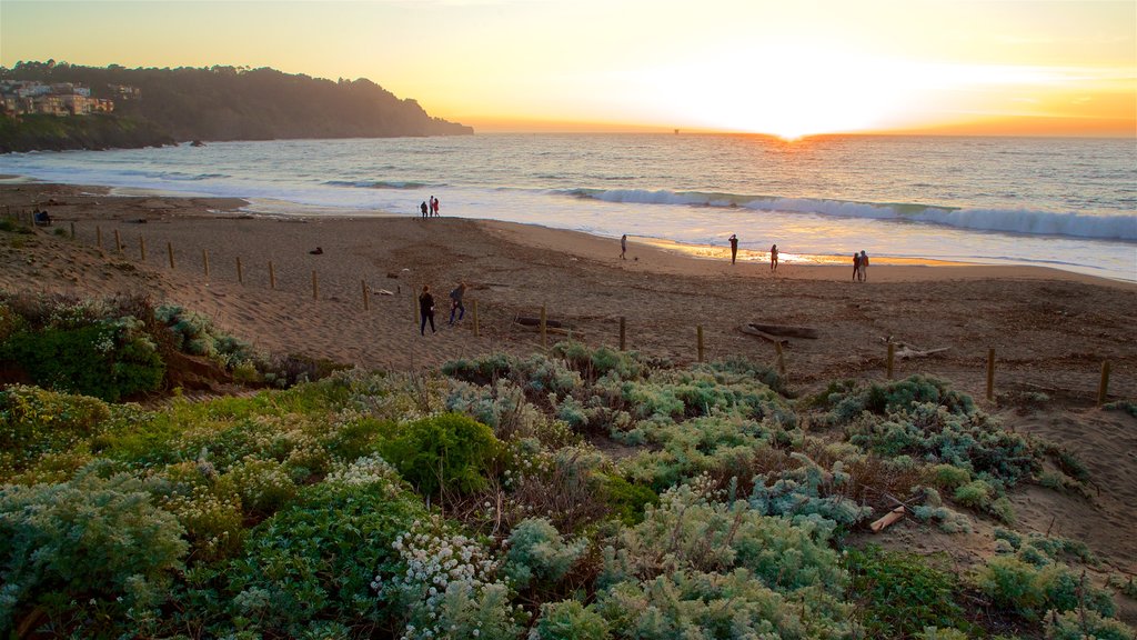 Playa Baker mostrando surf, una puesta de sol y vistas generales de la costa