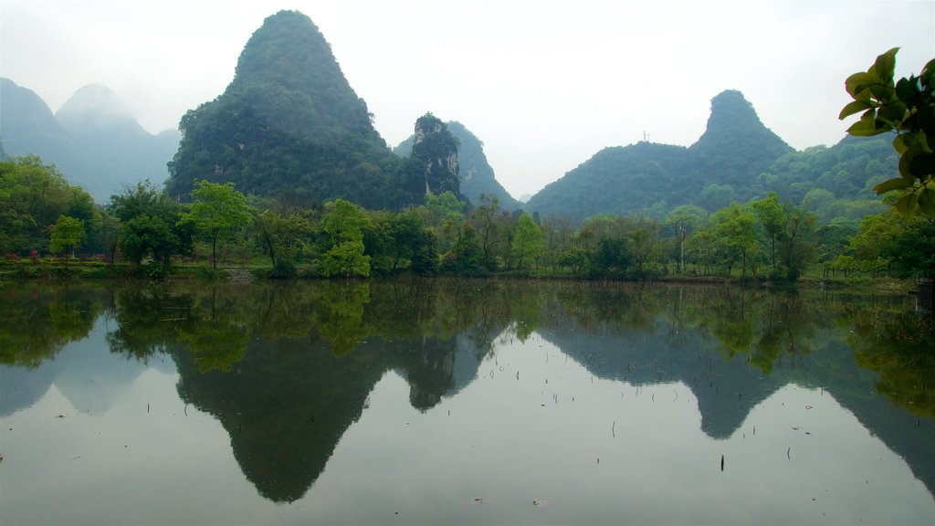 Yangshuo Park which includes a lake or waterhole, mist or fog and mountains