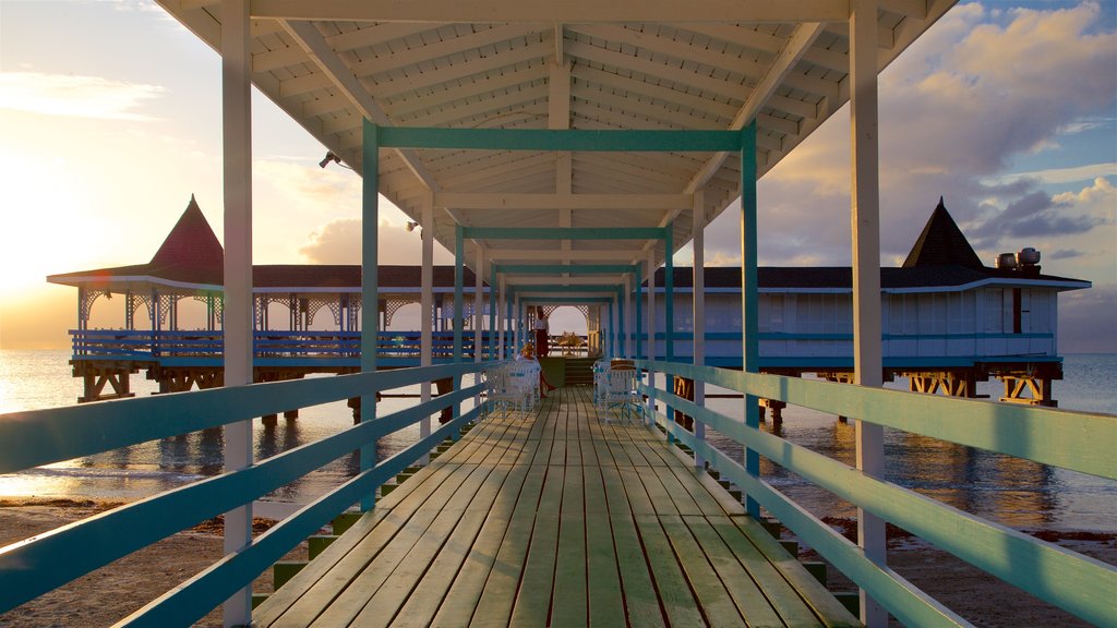 Dickenson Bay Beach caracterizando paisagens litorâneas, uma praia de areia e um pôr do sol