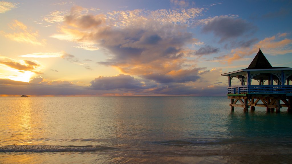 Dickenson Bay Beach que incluye un atardecer y vista general a la costa