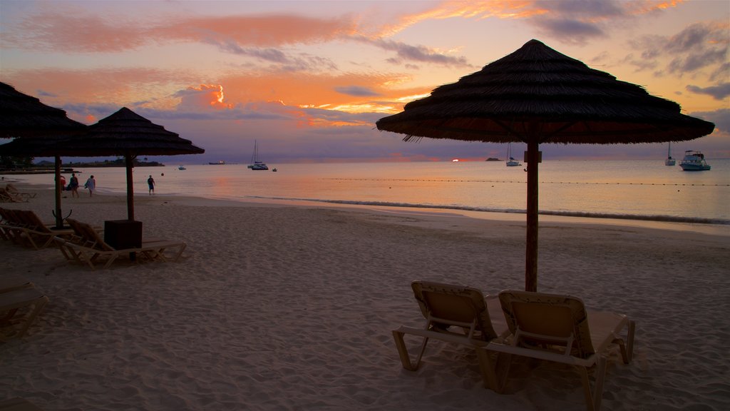 Dickenson Bay Beach ofreciendo un atardecer, una playa de arena y vista general a la costa