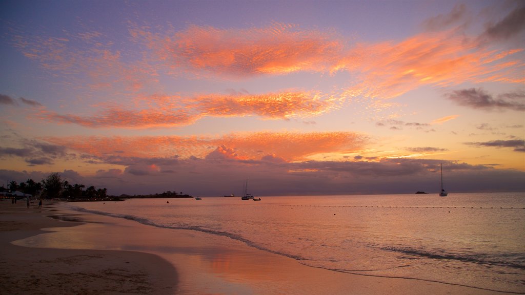 Dickenson Bay Beach que inclui um pôr do sol, uma praia de areia e paisagens litorâneas