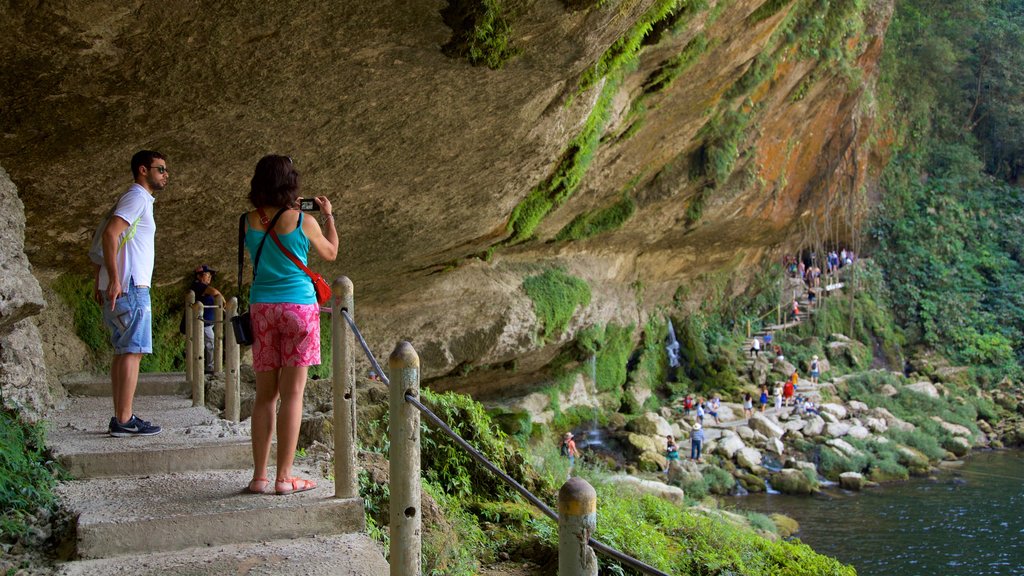 Misol-Ha Waterfalls featuring a gorge or canyon and a lake or waterhole as well as a couple