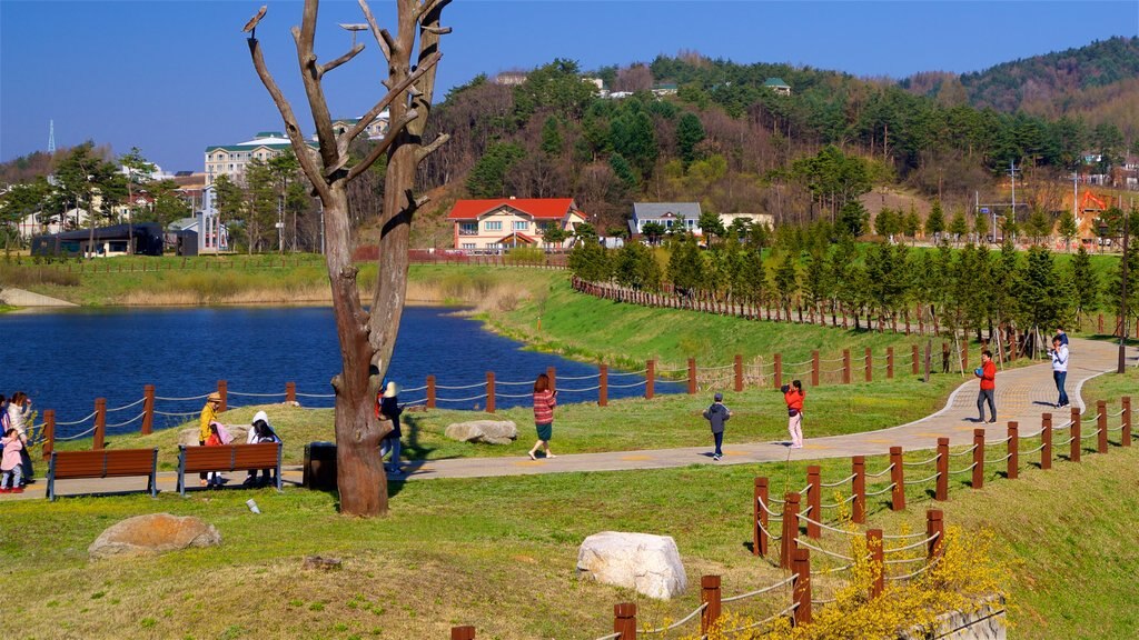 Estación de esquí Alpensia mostrando un lago o espejo de agua y jardín y también un pequeño grupo de personas