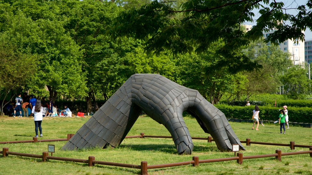 Yongsan Park featuring outdoor art and a garden as well as a small group of people