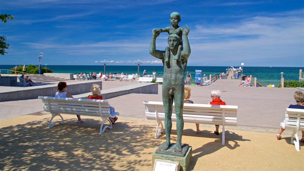 Kuehlungsborn Beach showing a statue or sculpture and general coastal views as well as a small group of people