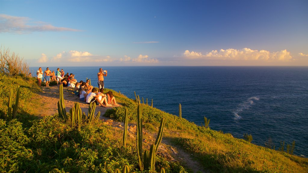 Atalaia Viewpoint featuring a sunset and general coastal views as well as a small group of people