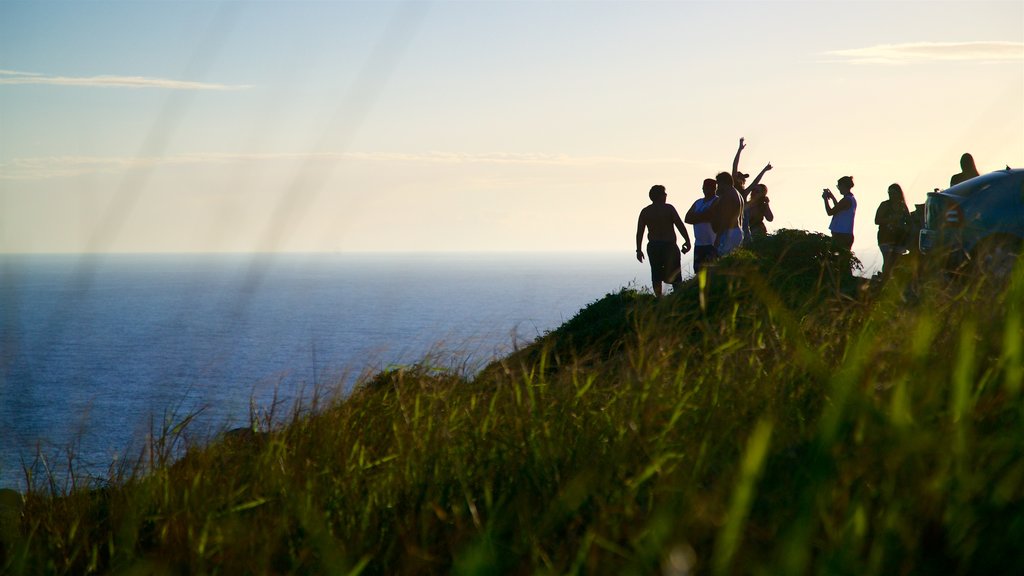 Mirador de Atalaia mostrando una puesta de sol y vistas generales de la costa y también un pequeño grupo de personas