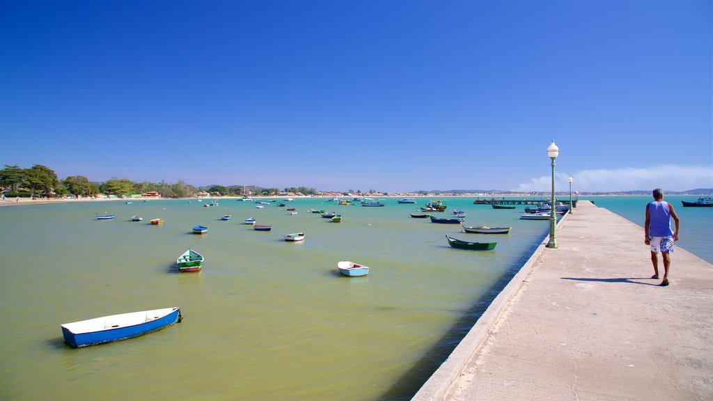 Playa de Manguinhos que incluye una bahía o un puerto y vista general a la costa y también un hombre