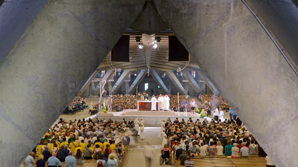 Basilique Saint-Pie X que inclui vistas internas e uma igreja ou catedral assim como um grande grupo de pessoas