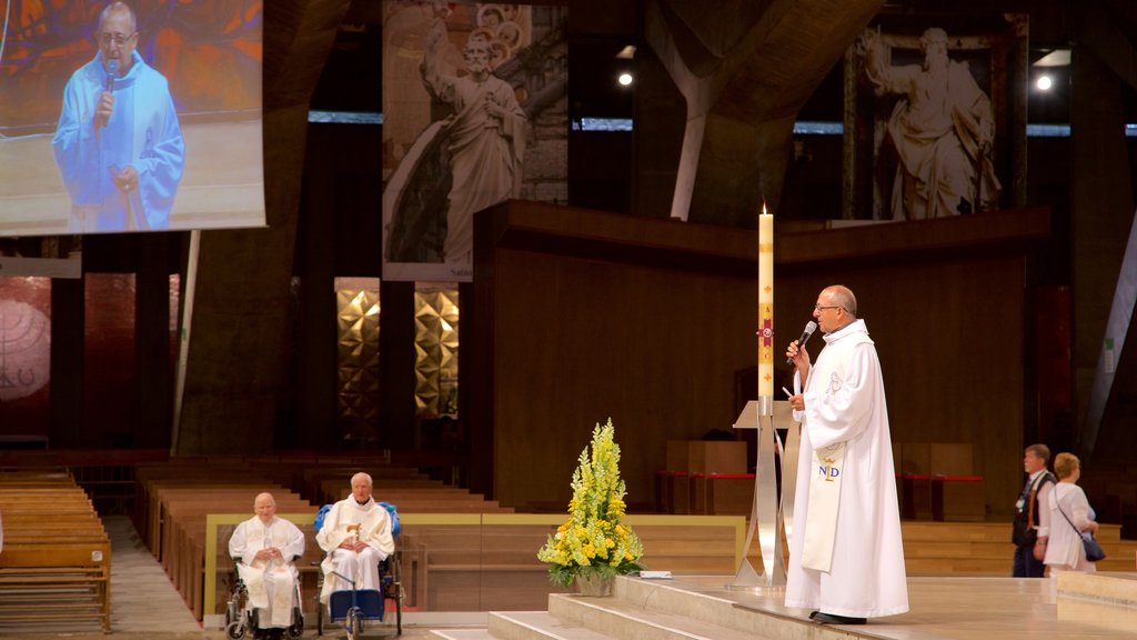 Basílica de San Pío X que incluye una iglesia o catedral y vistas interiores y también un pequeño grupo de personas