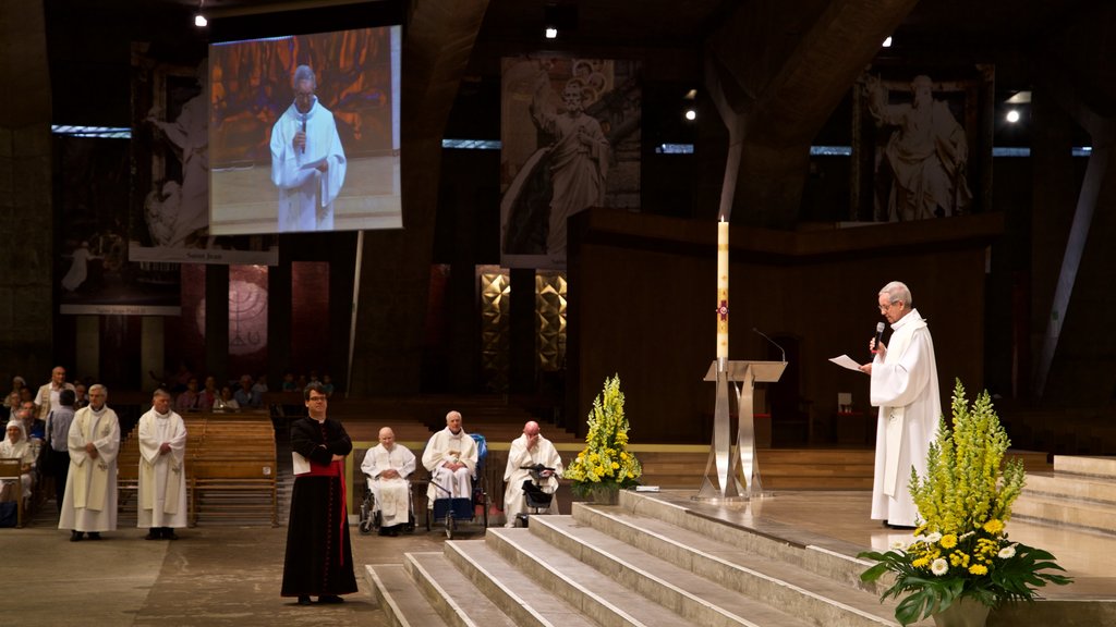 Basílica de San Pío X ofreciendo vista interna y una iglesia o catedral y también un pequeño grupo de personas