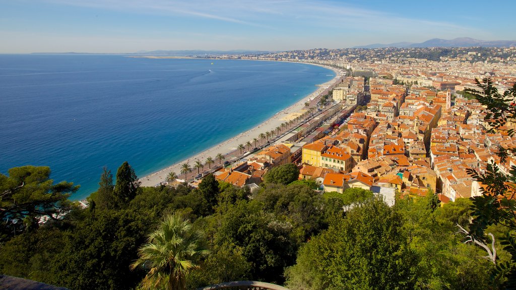 Niza que incluye una playa de guijarros, una ciudad costera y horizonte