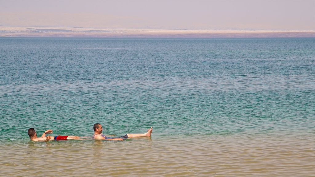 Playa Ammán ofreciendo vistas generales de la costa y natación y también un pequeño grupo de personas