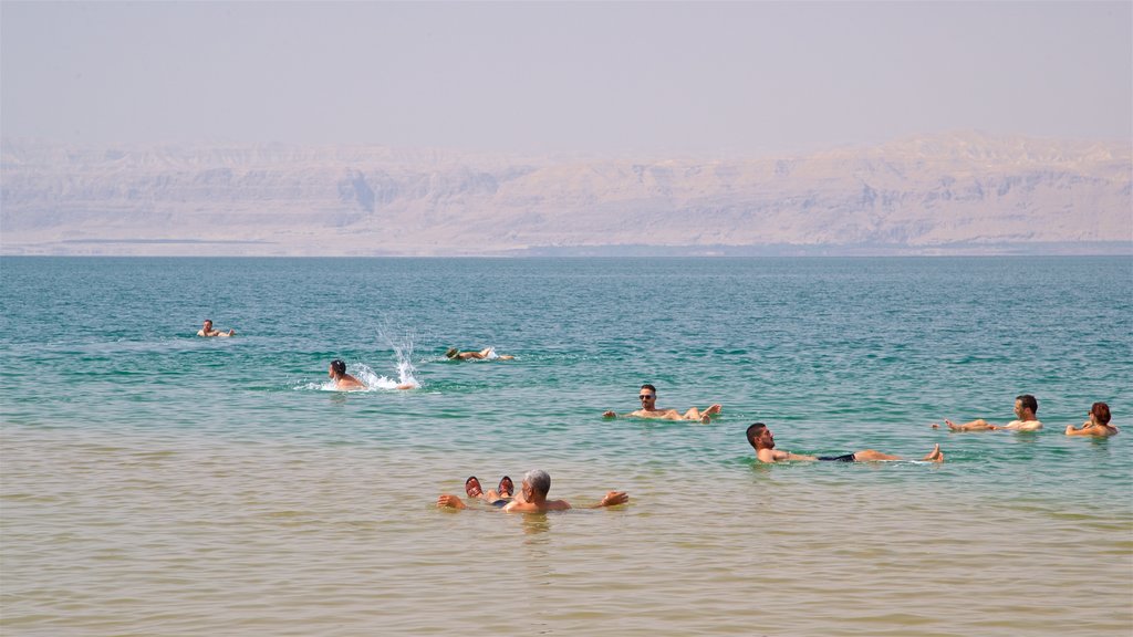 Playa Ammán ofreciendo vistas generales de la costa y natación y también un pequeño grupo de personas