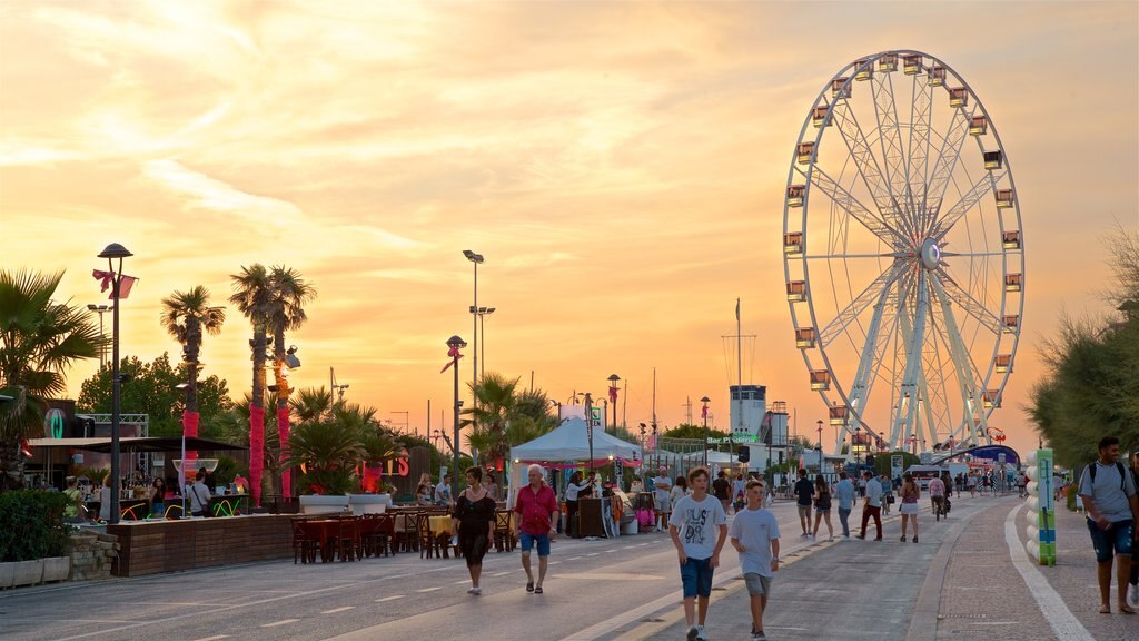 Roda Gigante de Rimini mostrando um pôr do sol assim como um pequeno grupo de pessoas