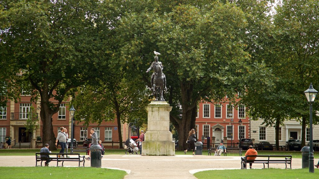 Queen Square which includes a statue or sculpture and a park as well as a small group of people