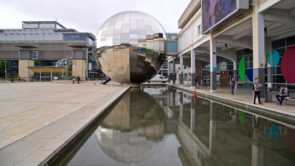 Millennium Square featuring outdoor art and a pond