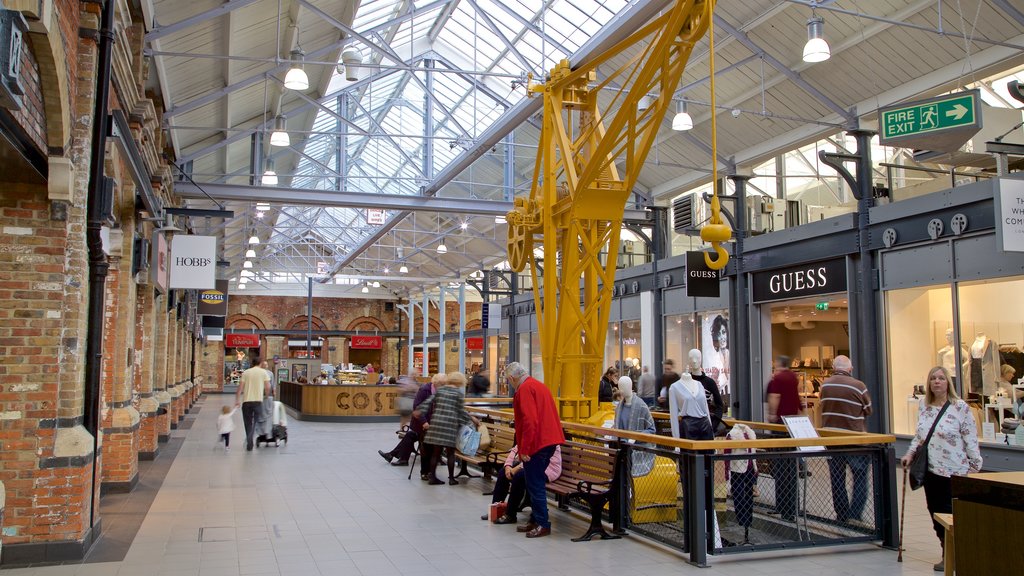 Swindon Designer Outlet mostrando shopping y vista interna y también un pequeño grupo de personas