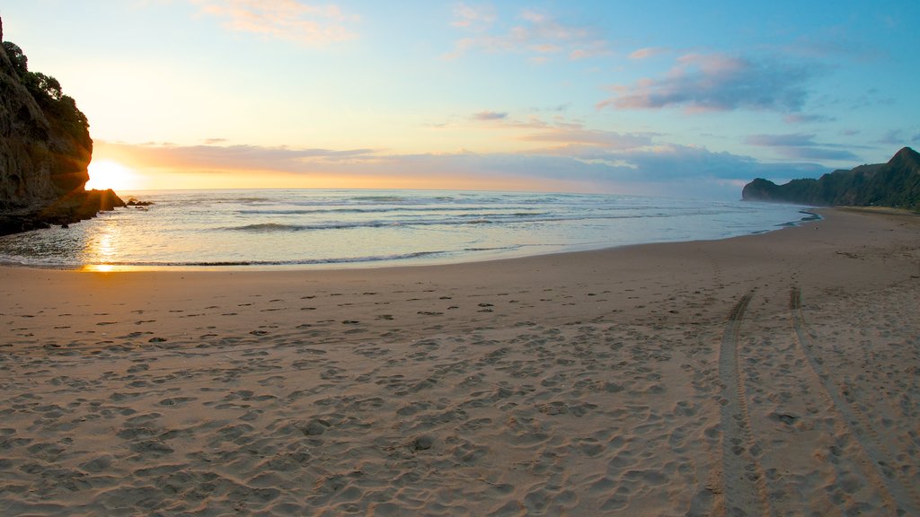 Piha Beach mostrando una puesta de sol, una playa y vistas de paisajes