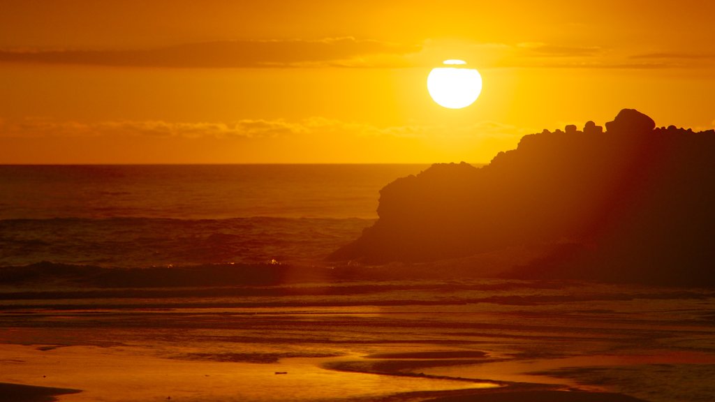 Piha Beach which includes general coastal views and a sunset