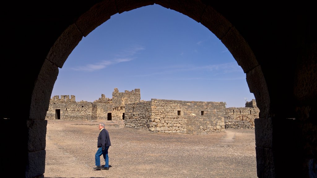 Qasr al-Azraq featuring heritage elements and desert views as well as an individual male