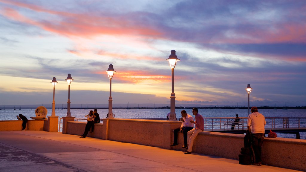 Malecon Kiosk which includes general coastal views and a sunset as well as a small group of people