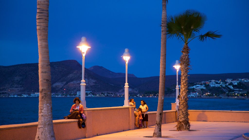 Malecon Kiosk which includes night scenes and general coastal views as well as a small group of people