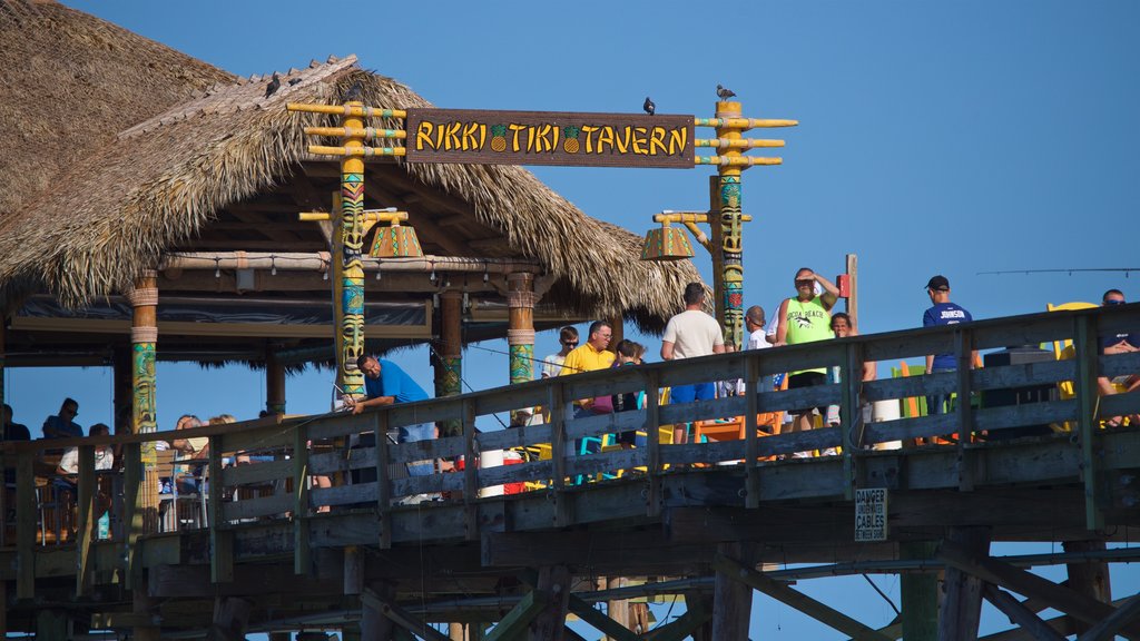 Cocoa Beach Pier que incluye señalización y también un pequeño grupo de personas