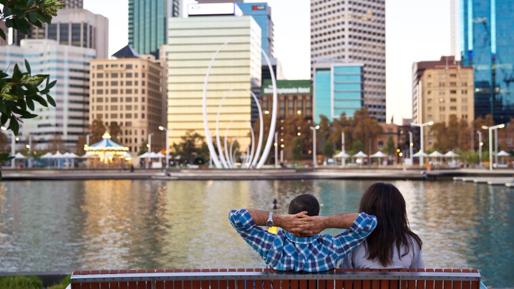 Parque Elizabeth Quay mostrando una ciudad y un lago o abrevadero y también una pareja