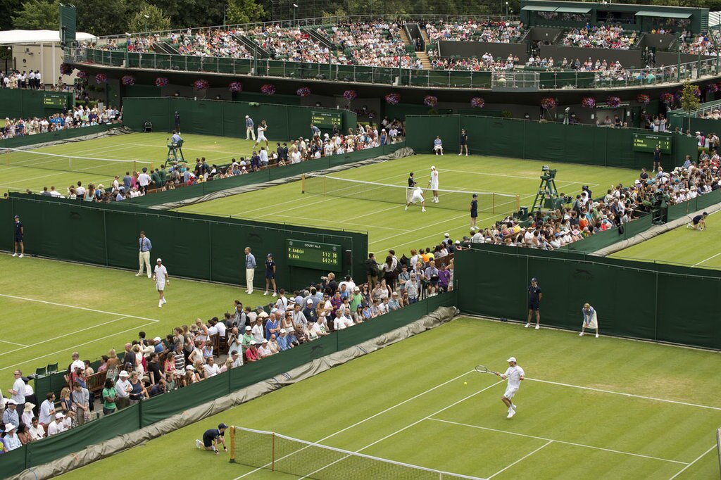 Gli spettatori guardano l'azione sui campi meridionali con il Court 2 in lontananza durante i Campionati 2014 presso l'All England Lawn Tennis & Croquet Club di Wimbledon. Credit: AELTC/Thomas Lovelock.