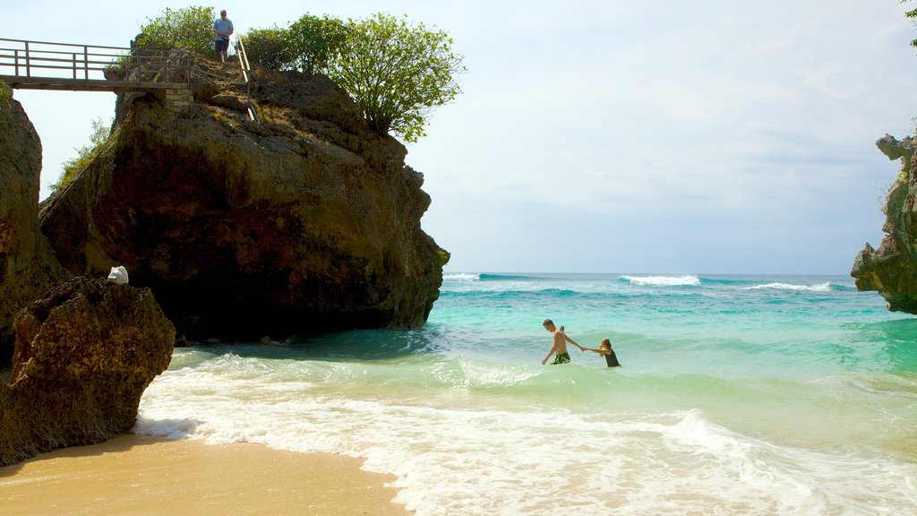 Praia de Uluwatu mostrando cenas tropicais, natação e uma praia de areia