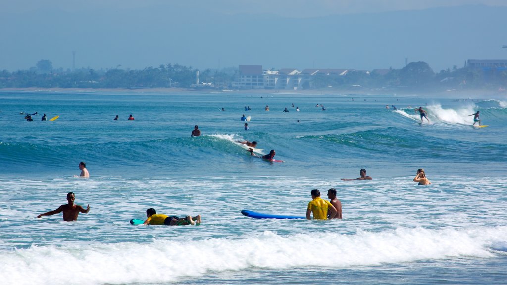 Playa de Kuta mostrando natación y surf y también un gran grupo de personas