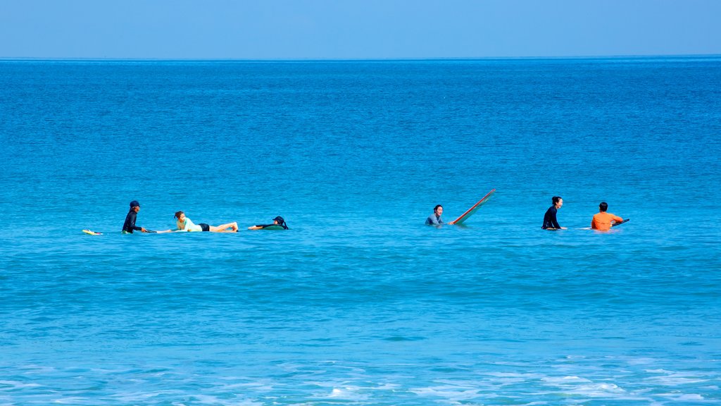 Legian Beach featuring surfing and waves as well as a large group of people